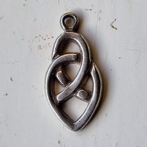 Puede incluir: Encanto de colgante de nudo celta de plata en forma de corazón. El nudo es intrincado y detallado.