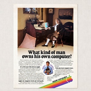 Puede incluir: Un anuncio vintage de Apple Computer que muestra a una persona con vestimenta del siglo XVIII sentada en un escritorio de madera con un ordenador. El texto dice: What kind of man owns his own computer? Incluye una imagen pequeña de una persona con una caja.
