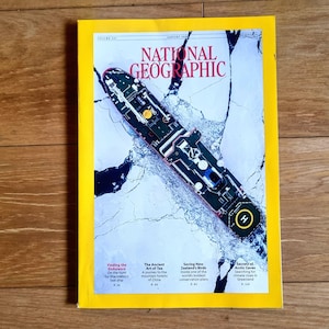 May include: A National Geographic magazine with a yellow border. The cover features a ship navigating icy waters. The magazine's title is in red and white. The January issue includes articles on exploration and the environment.