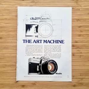 Op de afbeelding: Een advertentie voor de Minolta SR-T 303 camera. De advertentie toont een gedetailleerde technische tekening van de camera en een foto van de camera met een lens. De tekst luidt "THE ART MACHINE".