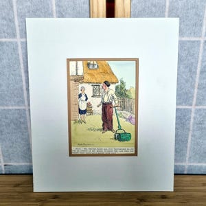 May include: A framed vintage print depicting a humorous cartoon scene. A man in a white shirt and red trousers pushes a green lawnmower. A woman in a maid's uniform stands nearby. The print includes text at the bottom.