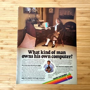 May include: An Apple Computer advert showing a man in historical clothing using a computer. The text asks "What kind of man owns his own computer?" and features the Apple logo with a rainbow design.