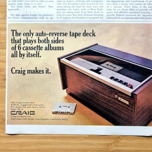 May include: An advertisement for a Craig auto-reverse tape deck. The deck is housed in a wood-grain cabinet with a cassette tape visible inside. The ad text reads, "The only auto-reverse tape deck that plays both sides of 6 cassette albums all by itself."