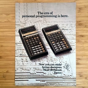 May include: Vintage advertisement featuring two black calculators with numerous buttons and a digital display. The text reads "The era of personal programming is here." and "Now you can make better decisions. More decisions. Faster."
