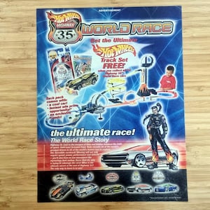 May include: A promotional advertisement for Hot Wheels Highway 35 World Race. The image features a blue background with a race track, toy cars, and the text "Get the Ultimate Hot Wheels Track Set FREE!". A cartoon figure stands next to a race car.