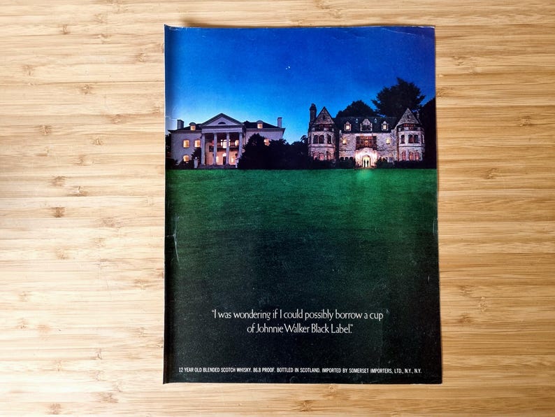 Original vintage Johnnie Walker Black Label magazine advertisement showing a nighttime view of illuminated historic mansion buildings set behind a dark lawn, featuring the brand’s famous whisky slogan and classic luxury Scotch advertising imagery, presented as an authentic collectible print with visible magazine fold.
