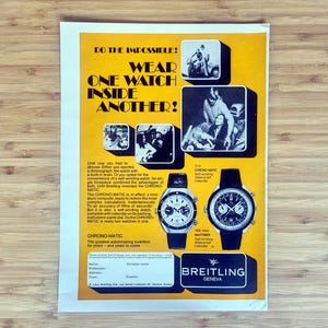 Könnte beinhalten: Vintage Breitling-Werbung mit dem Text "DO THE IMPOSSIBLE! WEAR ONE WATCH INSIDE ANOTHER!". Die Anzeige zeigt zwei Uhren, Illustrationen und das Breitling-Logo. Der Hintergrund ist gelb.