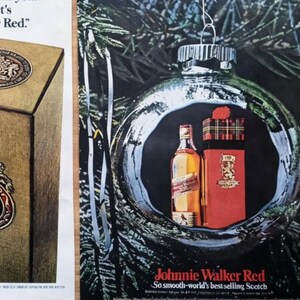 May include: An advertisement featuring a Johnnie Walker Red bottle and gift box inside a Christmas ornament. The bottle and box are red and gold, with the brand name prominently displayed. The background is a dark green with pine needles.