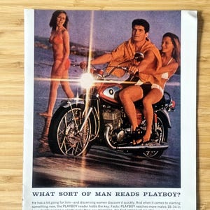May include: Vintage magazine advert showing a man on a red motorcycle with two women. The scene is set on a beach, with the text "WHAT SORT OF MAN READS PLAYBOY?" at the bottom of the image.