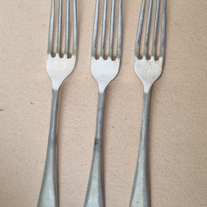 May include: Three silver forks with four tines each, arranged vertically. The forks have a simple, classic design with a rounded handle base. The forks are made of a shiny metal and are set against a neutral background.