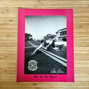 Puede incluir: Fotografía en blanco y negro de un skater en una carretera, con el texto "Free On The Streets" y el logotipo de Independent Truck Company. La imagen está enmarcada en un borde rosa brillante.