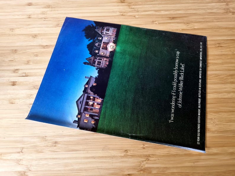 May include: A magazine with a blue and green gradient background featuring a nighttime landscape with illuminated buildings. Text on the magazine reads, "I was wondering if I could possibly borrow a cup of Johnnie Walker Black Label."
