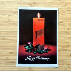 Original Johnnie Walker Red Label Christmas ad showing the pack styled as a glowing red candle, with holly and ornaments and the words “Happy Christmas”; approx. 11 × 7 in vintage magazine page, ideal for framing.