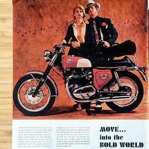 Pode incluir: Anúncio vintage de uma motocicleta BSA Spitfire MK IV vermelha e branca. A imagem mostra um casal posando na moto. O texto diz "MOVE... into the BOLD WORLD".