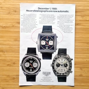 Op de afbeelding: Een advertentie van 1 december 1969 met drie Heuer chronografen met zwarte leren bandjes. De horloges hebben zwart-witte wijzerplaten met diverse wijzerplaten en het Heuer-logo. De tekst luidt: "Heuer chronografen zijn nu automatisch."