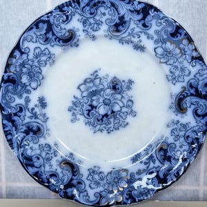 May include: A blue and white porcelain plate with a floral design. The plate has a scalloped edge and a raised rim.