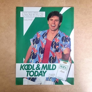 May include: Vintage magazine advertisement featuring a man in a patterned shirt holding a pack of Kool Milds cigarettes. The ad has a green and white background with the text "KOOL & MILD TODAY". A Surgeon General's warning is also present.