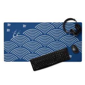 May include: A blue desk mat with a white wave pattern, a black keyboard, a black mouse, and black headphones. The desk mat measures approximately 36 inches long and 12 inches wide.