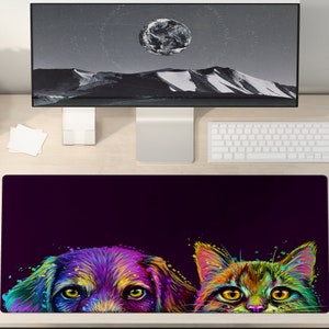 May include: A colourful desk mat with a dog and cat design. The dog is rendered in purple, yellow, and blue, and the cat in green, yellow, and orange. The background is a deep purple. The mat is designed for a desk.