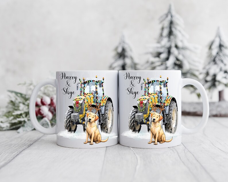 May include: Two white ceramic mugs with a festive design. Each mug features a yellow tractor decorated with lights, a golden Labrador, and the names "Harry & Skye" in elegant script. The mugs are set against a snowy backdrop.