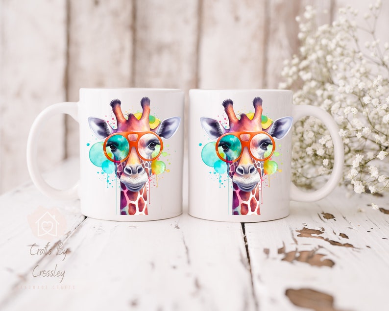 May include: Two white ceramic mugs with a colorful watercolor giraffe wearing orange sunglasses. The giraffe is surrounded by colorful watercolor splatters.
