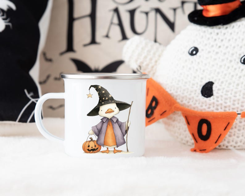 May include: White enamel mug featuring a cartoon duck dressed as a witch, holding a pumpkin and a staff. The duck wears a black witch hat with stars. The mug has a silver rim and a white handle. Halloween themed.