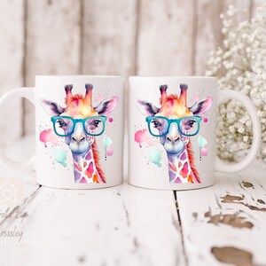 May include: Two white ceramic mugs with a watercolor illustration of a giraffe wearing blue glasses. The giraffe is surrounded by colorful watercolor splatters.