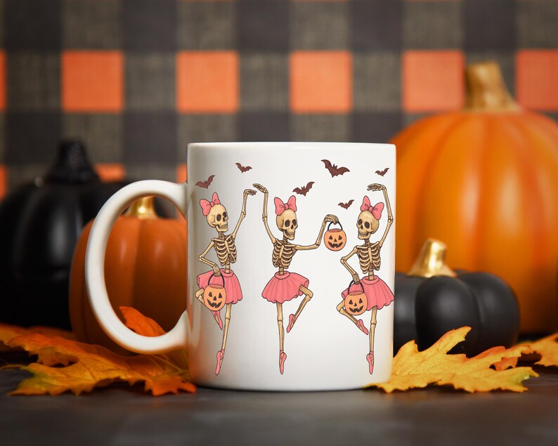 Pu&ograve; includere: Tazza in ceramica bianca con un design a tema Halloween. Il design presenta tre ballerine scheletro con tut&ugrave; e fiocchi rosa, che tengono lanterne a forma di zucca, circondate da pipistrelli. La tazza &egrave; ambientata su uno sfondo di zucche e foglie autunnali.