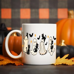Pu&ograve; includere: Tazza in ceramica bianca con un design di Halloween. Presenta fantasmi dei cartoni animati, gatti neri, pipistrelli e stelle. La tazza ha un manico bianco ed &egrave; ambientata sullo sfondo di zucche e foglie autunnali.