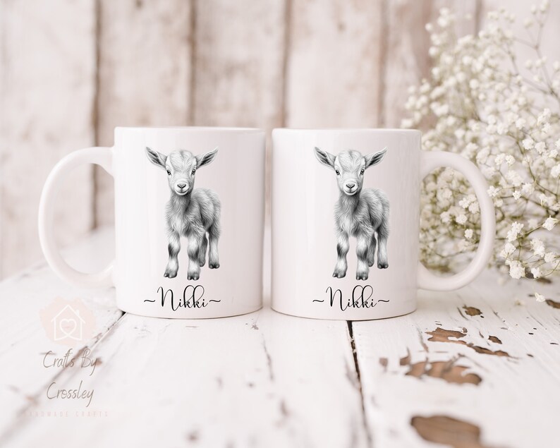 May include: Two white ceramic mugs with black handles. Each mug features a black and white illustration of a baby goat and the name "Nikki" written below the image.