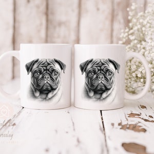 May include: Two white ceramic mugs with a black and white illustration of a pug dog's face on each mug.