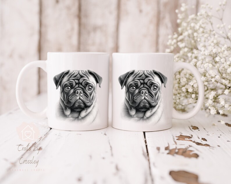 May include: Two white ceramic mugs with a black and white illustration of a pug dog's face on each mug.