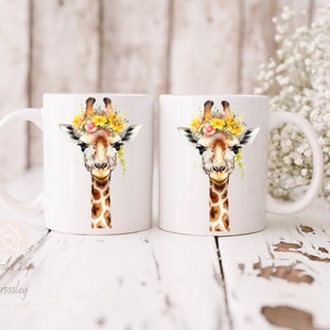 May include: Two white ceramic mugs with a giraffe wearing a flower crown printed on them. The giraffe has brown spots and a yellow flower crown.