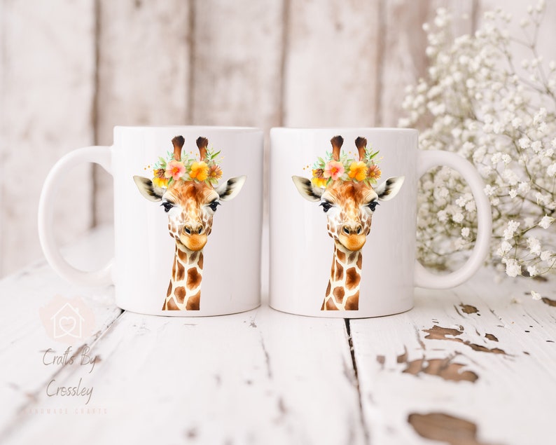 May include: Two white ceramic mugs with a watercolor illustration of a giraffe wearing a flower crown. The giraffe has a brown and white patterned coat and a friendly expression.