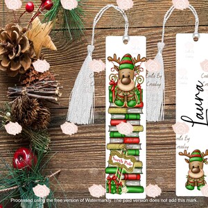 以下が含まれることがあります： 銀色のタッセルが付いた2つのクリスマスをテーマにしたブックマーク。1つは、本の上にいるトナカイのキャラクターが特徴で、「North Pole」というテキストがあります。もう1つのブックマークには、筆記体で「Laura」という名前があります。どちらにも「Crafts By Crossley」というテキストがあります。