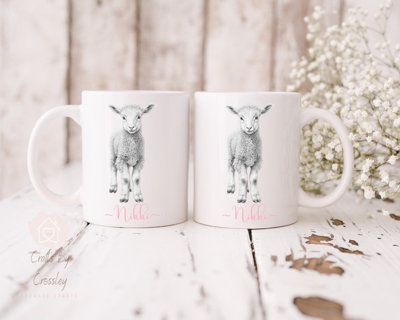 May include: Two white ceramic mugs with a black and white illustration of a lamb on each. The text "_Nikki_" is written in pink on the bottom of each mug.
