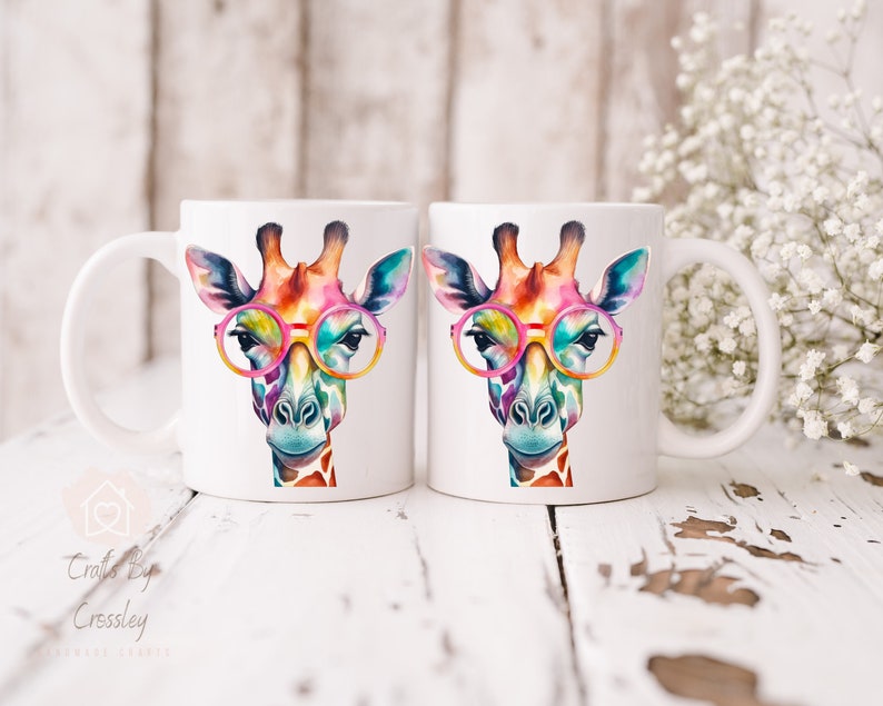 May include: Two white ceramic mugs with a colorful giraffe wearing pink glasses design. The giraffe has a watercolor effect and is looking directly at the viewer.