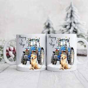 May include: Two white ceramic mugs with a festive design. Each mug features a blue tractor decorated with lights, a golden Labrador, and the text "Harry & Skye". The mugs are set against a snowy winter backdrop.