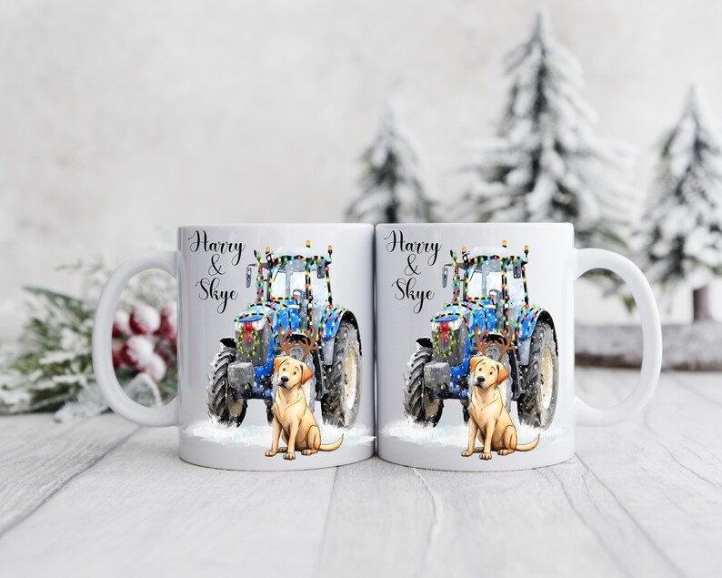 May include: Two white ceramic mugs with a festive design. Each mug features a blue tractor decorated with lights, a golden Labrador, and the text "Harry & Skye". The mugs are set against a snowy winter backdrop.