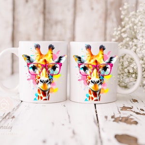 May include: Two white ceramic mugs with a colorful watercolor giraffe wearing pink glasses. The giraffe is surrounded by colorful paint splatters.