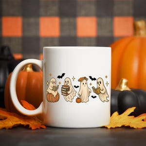 Pu&ograve; includere: Tazza in ceramica bianca con un design a tema Halloween. Presenta fantasmi dei cartoni animati che leggono libri, seduti su zucche e circondati da pipistrelli e stelle. Lo sfondo include zucche e foglie autunnali.