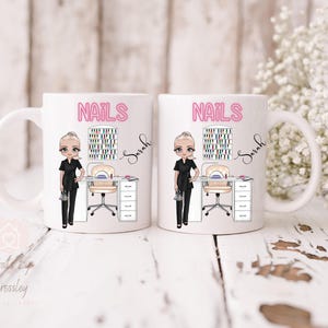 May include: Two white ceramic mugs with a nail salon theme. Each mug features the word "NAILS" in pink, a cartoon nail technician, and a nail polish display. The name "Sarah" is written in cursive.