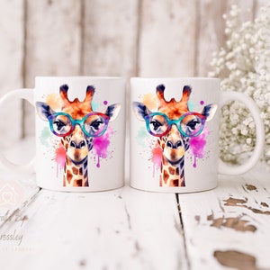 May include: Two white ceramic mugs with a watercolor design of a giraffe wearing glasses. The giraffe is surrounded by colorful paint splatters.