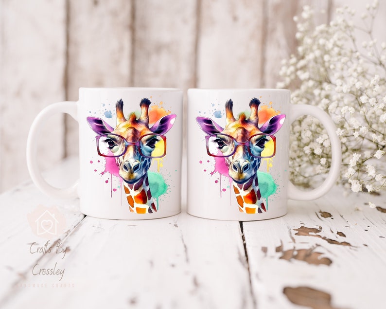 May include: Two white ceramic mugs with a colorful watercolor giraffe wearing glasses design. The giraffe has a pink, yellow, and blue watercolor background.