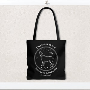 May include: Black tote bag with a white design of a constellation shaped like a beagle dog. The design includes the text "CONSTELLATION BEAGLEUS AROOMIUM Baying Beagle".