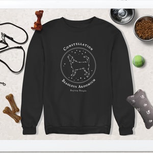 May include: Black sweatshirt with a white graphic of a beagle constellation with the text "Constellation Beagleus Aroomium Baying Beagle".