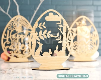May include: Three wooden Easter egg decorations. The center egg features a cutout design of a forest scene with two bunnies. The egg on the left has a cutout design of a floral pattern with the words "Happy Easter". The egg on the right has a cutout design of a geometric pattern.
