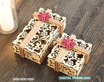 May include: Two intricately designed wooden boxes with floral patterns and a ribbon tied around them. The boxes are made of light wood and have a delicate, intricate design. The ribbon is a light brown color and is tied in a bow on top of each box. The boxes are sitting on a wooden surface.