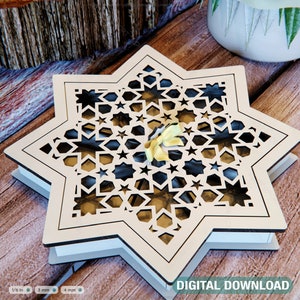 May include: A white wooden box with a star-shaped design. The box has a geometric pattern of stars and circles cut out of the wood. The box is sitting on a wooden surface.
