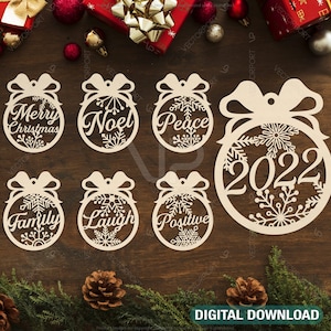 May include: Set of eight wooden Christmas ornaments with various holiday greetings and designs. The ornaments are round and feature a snowflake pattern. The greetings include "Merry Christmas", "Noel", "Peace", "2022", "Family", "Laugh", "Positive", and "Joy".